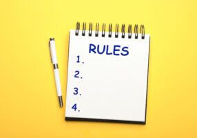 Stylish open notebook and pen on yellow background, top view