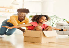 mother pushing his daughter sitting in a cardboard box, having fun at home