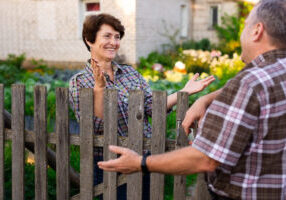 neighbors middle aged man and woman chatting near the fence in the village